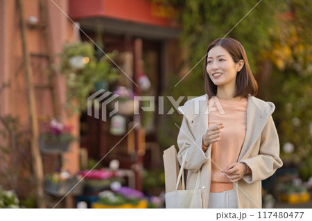 ハーフコートを着て買い物に行くミドルの女性 117480477