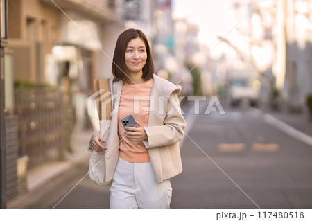 ハーフコートを着て買い物に行くミドルの女性 117480518