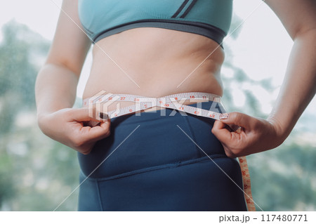 fat woman, fat belly, chubby, obese woman hand holding excessive belly fat with measure tape, woman diet lifestyle concept fat woman, fat belly, chubby, obese woman hand holding excessive belly fat with measure tape, woman diet lifestyle concept 117480771