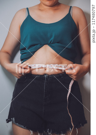 fat woman, fat belly, chubby, obese woman hand holding excessive belly fat with measure tape, woman diet lifestyle concept fat woman, fat belly, chubby, obese woman hand holding excessive belly fat with measure tape, woman diet lifestyle concept 117480797