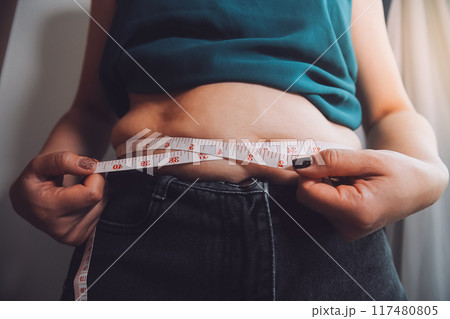 fat woman, fat belly, chubby, obese woman hand holding excessive belly fat with measure tape, woman diet lifestyle concept fat woman, fat belly, chubby, obese woman hand holding excessive belly fat with measure tape, woman diet lifestyle concept 117480805