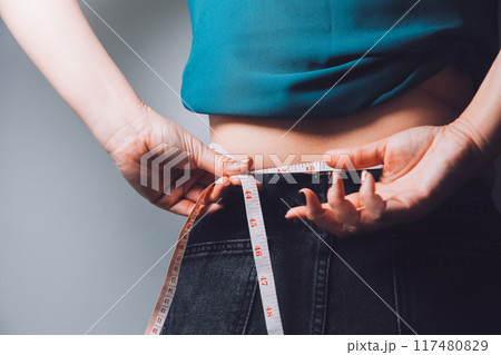 fat woman, fat belly, chubby, obese woman hand holding excessive belly fat with measure tape, woman diet lifestyle concept 117480829