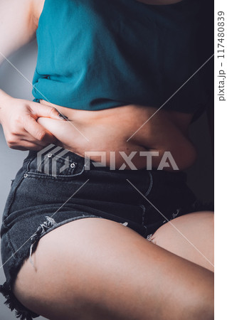 fat woman, fat belly, chubby, obese woman hand holding excessive belly fat with measure tape, woman diet lifestyle concept fat woman, fat belly, chubby, obese woman hand holding excessive belly fat with measure tape, woman diet lifestyle concept 117480839