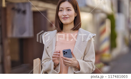 ハーフコートを着て買い物に行くミドルの女性 117481003
