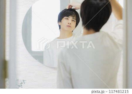 洗面所で鏡を見る若い男性 洗面所で鏡を見る若い男性 117481215