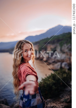 Young woman with long hair enjoying a sunset by the coastal cliffs on a warm evening 117481400