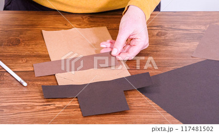 Step by step. Teacher guides online class through making a paper puppet from a brown bag, creatively using a wooden surface as a workspace. Step by step. Teacher guides online class through making a paper puppet from a brown bag, creatively using a wooden surface as a workspace. 117481502