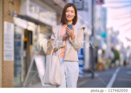 ハーフコートを着て買い物に行くミドルの女性 117482050