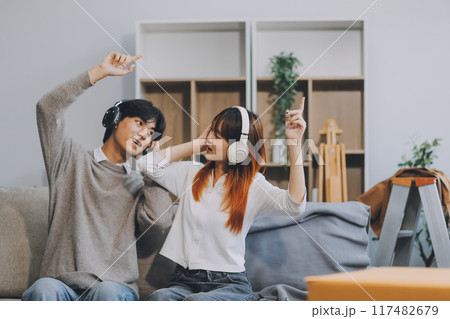 Asian Female discussing new project with male colleague. Young woman talking with young Asian man with financial on sofa in home office 117482679