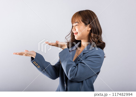 Asian happy portrait beautiful cute young woman smile standing presenting product holding something on palm away side, studio shot isolated on white background copy space, female show hand gesture Asian happy portrait beautiful cute young woman smile standing presenting product holding something on palm away side, studio shot isolated on white background copy space, female show hand gesture 117482994