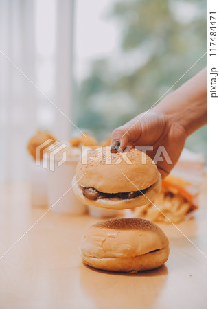 Binge eating disorder concept with woman eating fast food burger, fired chicken , donuts and desserts 117484471