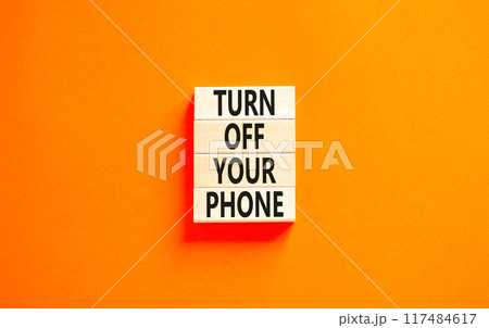Turn off your phone symbol. Concept words Turn off your phone on wooden blocks. Beautiful orange table orange background. Business, psychological turn off your phone concept. Copy space. 117484617