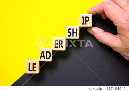 Leadership symbol. Concept word Leadership on beautiful wooden cubes. Beautiful yellow and black background. Businessman hand. Business leadership concept. Copy space. Leadership symbol. Concept word Leadership on beautiful wooden cubes. Beautiful yellow and black background. Businessman hand. Business leadership concept. Copy space. 117484642
