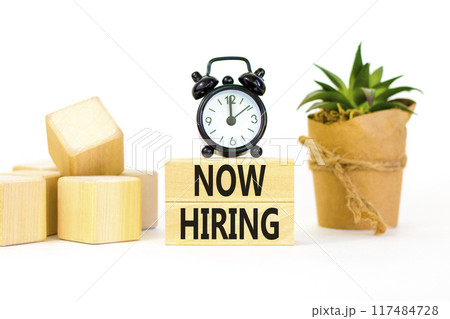 Now hiring symbol. Concept words Now hiring on beautiful wooden block. Beautiful white table white background. Black alarm clock. Business marketing, motivational now hiring concept. Copy space. 117484728