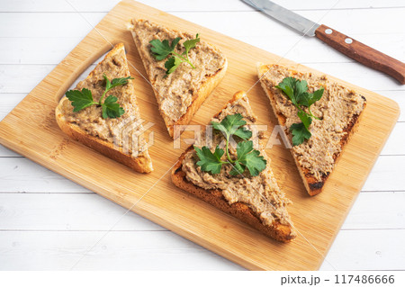 Sandwiches crispy toast and chicken liver pate with parsley leaves on a wooden cutting board. Copy space. 117486666