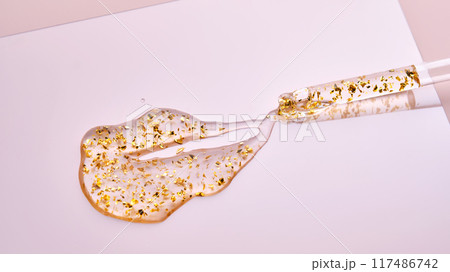 Pipette with 24k gold serum on a pink background. Pipette with 24k gold serum on a pink background. 117486742