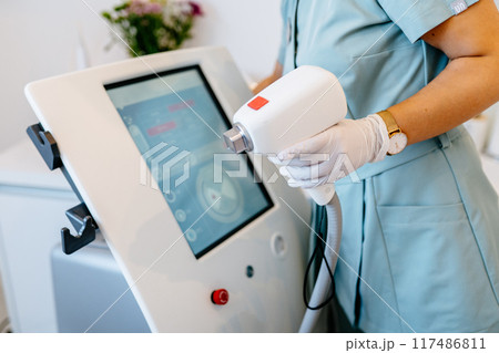 Hair removal procedure. Close up of women's hands with monitor and laser equipment for beauty procedure. Hair removal procedure. Close up of women's hands with monitor and laser equipment for beauty procedure. 117486811