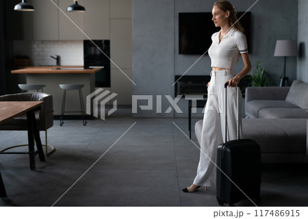 A young woman with a suitcase arrives at a vacation rental. A young woman with a suitcase arrives at a vacation rental. 117486915
