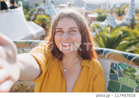 Beautiful 30s female in Gaudi garden, Spain, Barcelona. Young traveling woman taking selfie outdoors. Concept of travel, tourism and vacation in city. High quality photo Beautiful 30s female in Gaudi garden, Spain, Barcelona. Young traveling woman taking selfie outdoors. Concept of travel, tourism and vacation in city. High quality photo 117487018