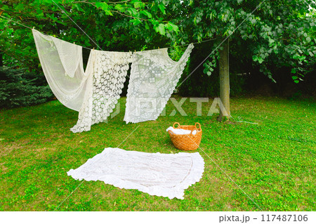 White laundry on clothesline in garden. White curtains drying in the sun. White laundry on clothesline in garden. White curtains drying in the sun. 117487106
