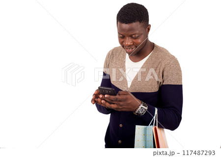 young smiling man with shopping bags is using a mobile phone young smiling man with shopping bags is using a mobile phone 117487293