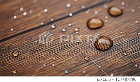 Water droplets resting on a wooden surface in soft natural light 117487796