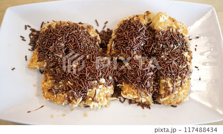 Appetizer or fried banana snack menu topped with grated cheese and chocolate. 117488434