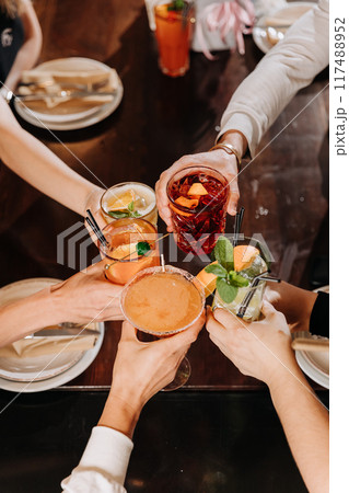 Top view of friends toasting with colorful cocktails at a lively gathering, celebrating togetherness 117488952
