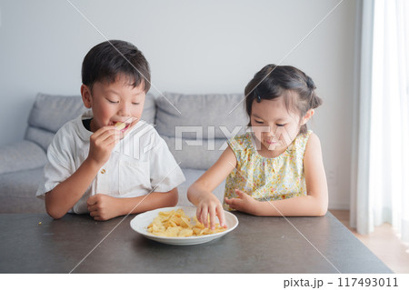 お菓子のポテトチップスを食べる子供 117493011