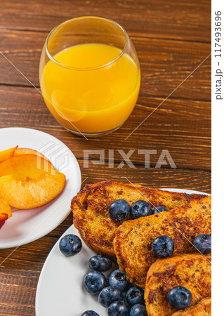 French toast on a plate with blueberries, orange juice, nectarine for breakfast French toast on a plate with blueberries, orange juice, nectarine for breakfast 117493696