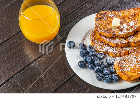 French toast on a white plate with blueberries and orange juice for breakfast French toast on a white plate with blueberries and orange juice for breakfast 117493707