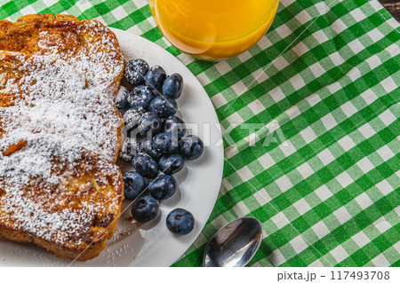 French toast on a white plate with blueberries and orange juice for breakfast French toast on a white plate with blueberries and orange juice for breakfast 117493708