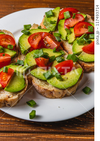 Avocado toast topped with tomato and green onion on a slice of carrot bread 117493714