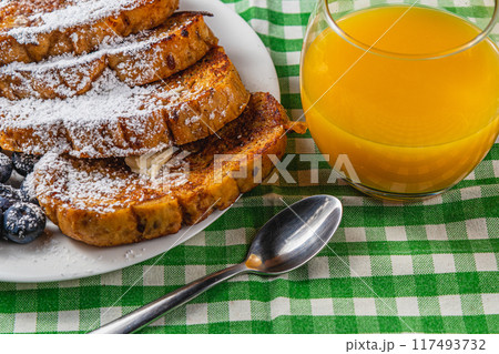 French toast on a white plate with blueberries and orange juice for breakfast 117493732