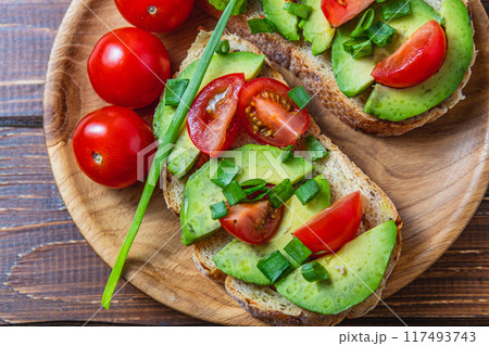 Avocado toast topped with tomato and green onion on a slice of carrot bread 117493743