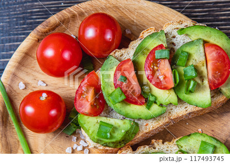 Avocado toast topped with tomato and green onion on a slice of carrot bread 117493745