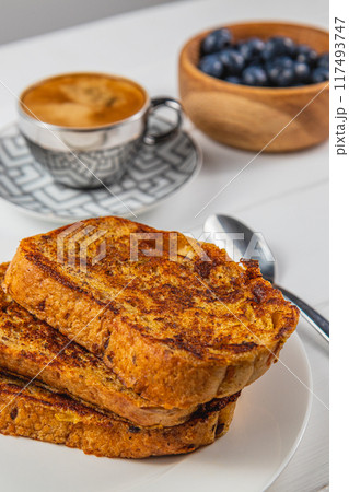 French toast on a white plate with blueberries and coffee for breakfast French toast on a white plate with blueberries and coffee for breakfast 117493747