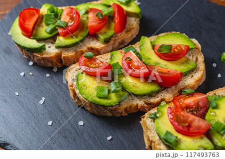 Avocado toast topped with tomato and green onion on a slice of carrot bread 117493763