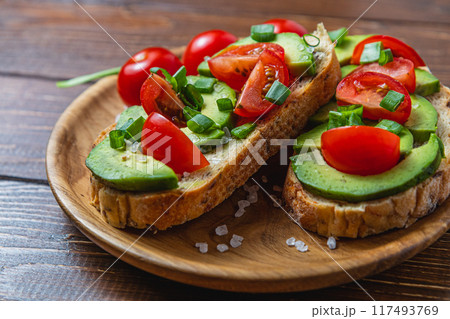 Avocado toast topped with tomato and green onion on a slice of carrot bread 117493769