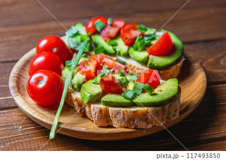Avocado toast topped with tomato and green onion on a slice of carrot bread 117493850