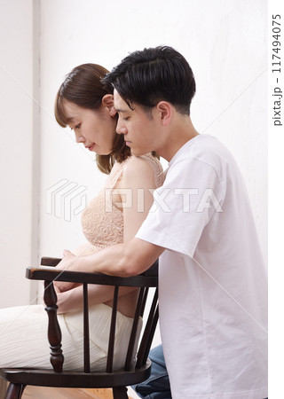 椅子に座った若い妊婦と寄り添う夫 椅子に座った若い妊婦と寄り添う夫 117494075