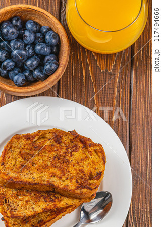 French toast on a white plate with blueberries and orange juice for breakfast French toast on a white plate with blueberries and orange juice for breakfast 117494666