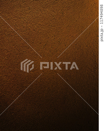 濃く暗い茶色の土壁のなかに藁の風合いが残る表面の縦長の背景画像 117494898