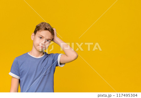 Teenage troubles. Confused boy scratching his head with puzzled expression, orange background. Teenage troubles. Confused boy scratching his head with puzzled expression, orange background. 117495304