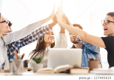 Successful college students putting their hands up in library, celebrating their graduation exams 117495814