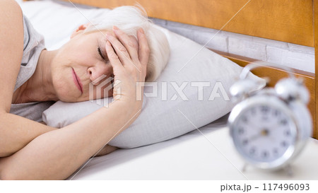 Worried senior woman suffering from insomnia, having headache in bed, touching her forehead, panorama Worried senior woman suffering from insomnia, having headache in bed, touching her forehead, panorama 117496093
