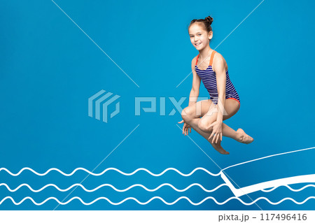 A young girl, wearing a blue and white striped swimsuit, is captured mid-air as she jumps over an illustrated pool. The background is a vibrant blue, copy space 117496416