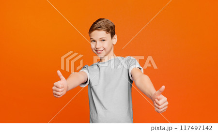 Like. Cool boy doing thumbs up gesture on orange studio background 117497142