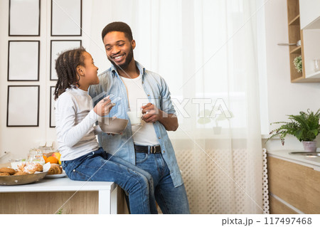 Friendly african family having breakfast together in kitchen, father and daughter talking and joking, panorama with copy space 117497468