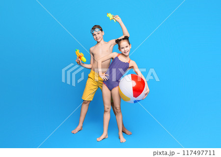 Happy summer holidays. Cheerful boy and girl playing with beach toys, blue studio background 117497711